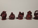 a group of five red carved figurines of buddhas