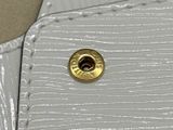 un gros plan sur un sac à main blanc orné d'un bouton doré