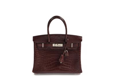a brown leather handbag with a tassel on top of it