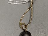 necklace with a black pearl and a gold chain on a gray surface