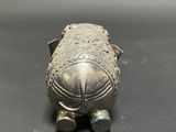 an old silver figurine of a fish on a black surface