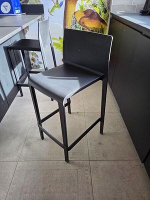 une chaise noire posée dans une cuisine, à côté d'un réfrigérateur
