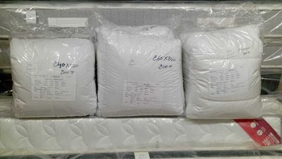 three bags of white pillows sitting on top of each other