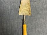 une spatule à manche jaune en bois posée sur une surface grise
