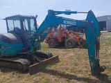 a blue excavator that is sitting in the grass