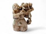 une petite figurine en ivoire représentant une femme tenant un bébé dans ses bras