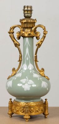 a green vase on a table with a gold base