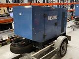 une remorque transportant une machine bleue, dans un entrepôt