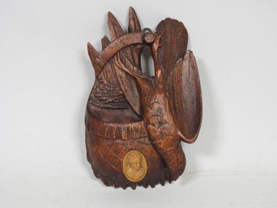 wooden carving of a bird holding a coin on a white surface