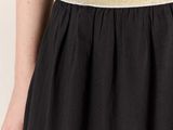 the back of a woman wearing a black dress with a gold belt