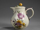 a white pitcher with flowers and a bird on top of it