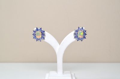 une paire de boucles d'oreilles en oplite et saphir bleu, présentées sur un socle blanc