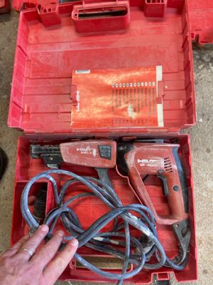 une personne tenant une perceuse filaire dans une boîte rouge