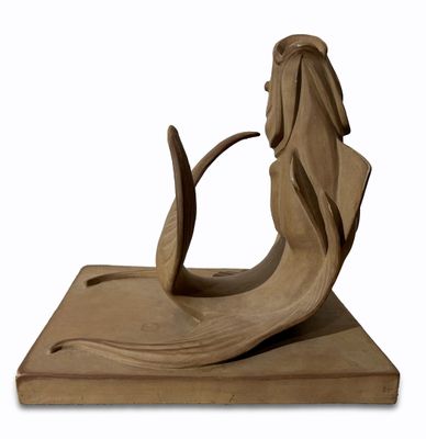 statue of a mermaid with a long tail sitting on a block