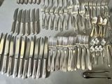 a lot of silver spoons and forks laid out on a table