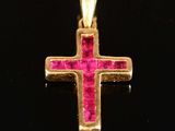 a close up of a gold cross with pink stones on a black surface