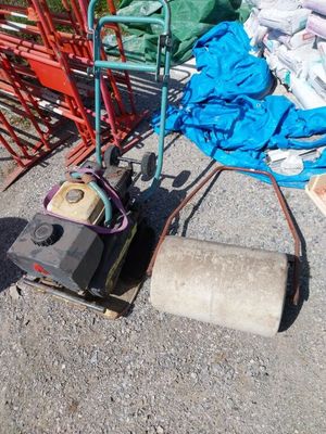 une tondeuse à gazon posée sur le bord de la route, à côté d'un tas de sacs