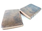 two old books sitting next to each other on a white surface