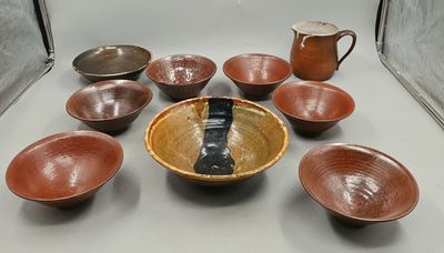 many bowls and cups on the table with a pitcher