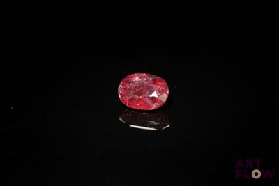 un diamant rouge sur une surface noire dans l'obscurité