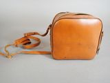 a brown leather bag with a strap on a white background