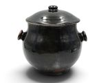 une casserole noire avec un couvercle posée sur une surface blanche
