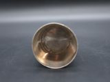 an antique silver cup on a table with a black background