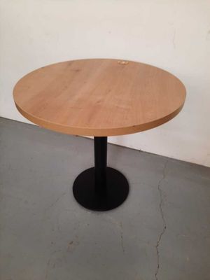 a round wooden table with a black metal base