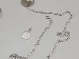 a silver necklace with a coin on it next to other silver items