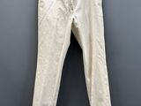 a white pants hanging on a hanger against a gray wall