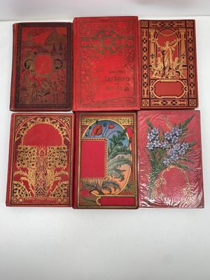 quatre livres rouges ornés de motifs dorés, posés sur une surface blanche