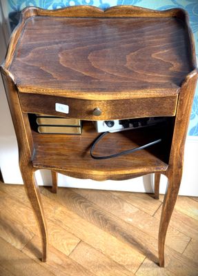 une petite table en bois avec un tiroir et un téléphone posé dessus