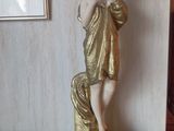 une statue représentant une femme debout sur une table en bois