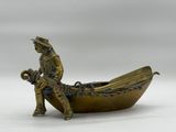 bronze figurine of a man sitting in a boat with a dog