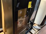 un réfrigérateur noir posé sur une palette dans un entrepôt
