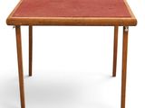 une petite table avec un plateau rouge et des pieds en bois
