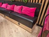 un canapé noir orné de coussins roses dans une pièce