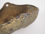 an old brass bowl on a white surface with a hole in the middle
