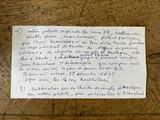 une écriture manuscrite sur une feuille de papier posée sur une table en bois