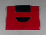 a red purse with a black handle sitting on a table