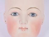 une tête de poupée aux yeux bleus sur un fond blanc