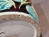 a close up of a vase with flowers painted on it