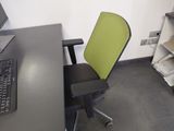 a green office chair next to a computer on a desk