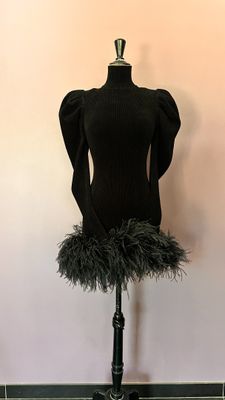 une photo d'un mannequin portant une jupe en plumes, posé sur un socle