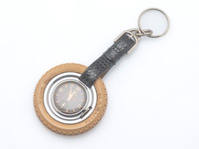 un porte-clés en cuir orné d'une montre, posé sur un fond blanc