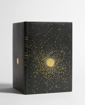 un livre noir orné d'étoiles dorées, posé sur une surface blanche