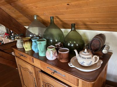 de nombreux vases de toutes sortes posés sur un meuble en bois dans une pièce