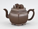 an image of a brown teapot with a cat on top
