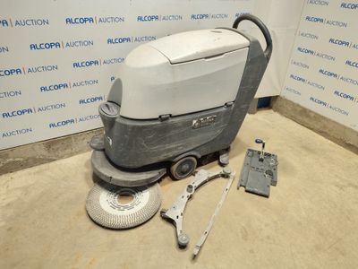 La machine à nettoyer les sols est posée par terre, près du mur.