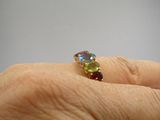 la main d'une personne tenant une bague sertie de pierres multicolores